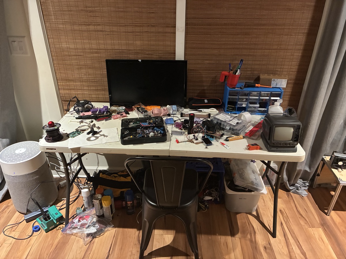 Nash's electronics workbench with CRT TV, arcade buttons, PCBs, and microcontrollers